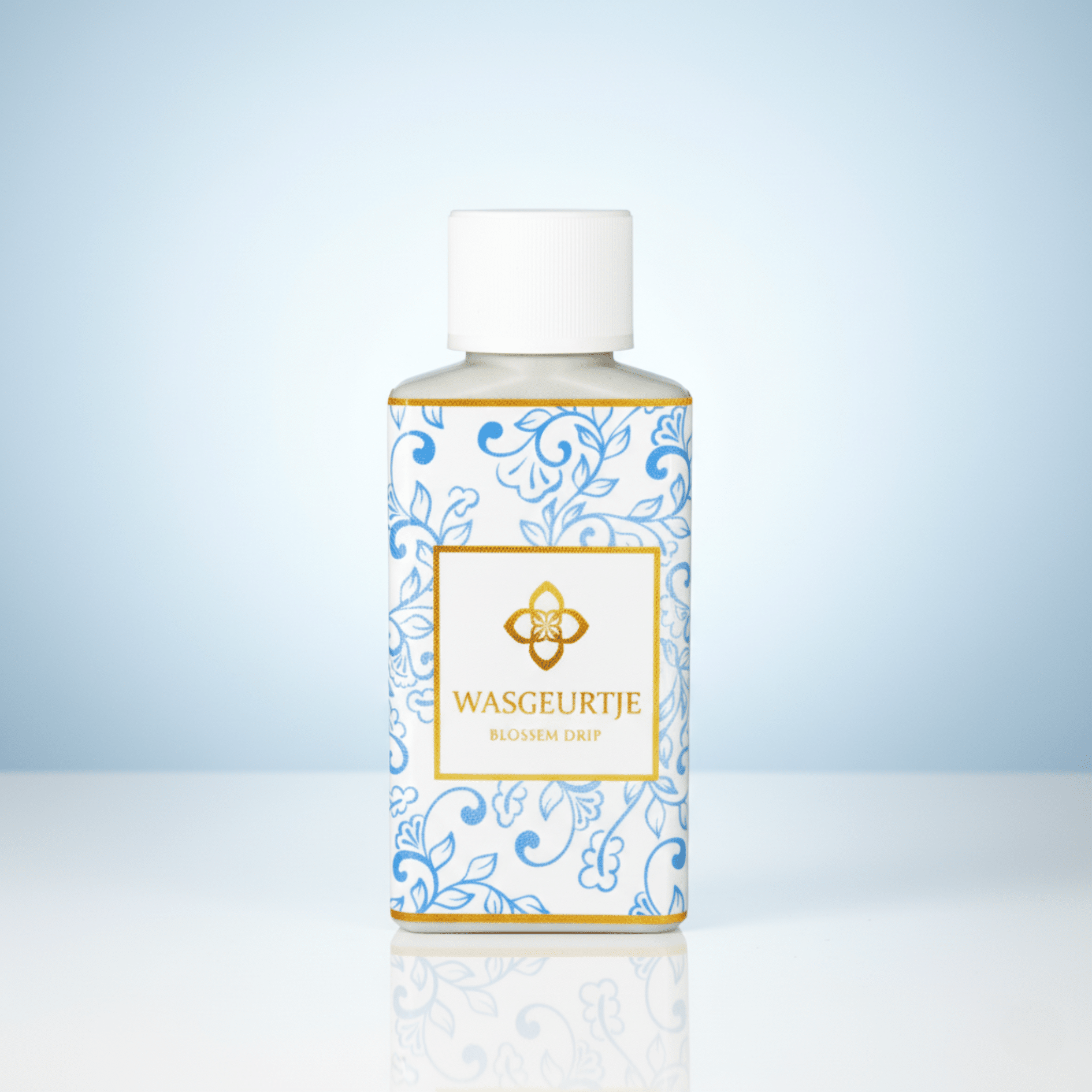 Flesje Wasgeurtje Blossom Drip wasparfum met blauw-wit bloemenpatroon op glanzend oppervlak, tegen een zachte lichtblauwe achtergrond.