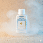 Flesje Wasgeurtje Flower Rain wasparfum op zacht zand met nevelige damp eromheen, in warme natuurlijke verlichting.