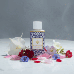 Flesje Wasgeurtje Full Moon wasparfum tussen kleurrijke bloembladen in rood, roze, wit en blauw op een marmeren oppervlak.